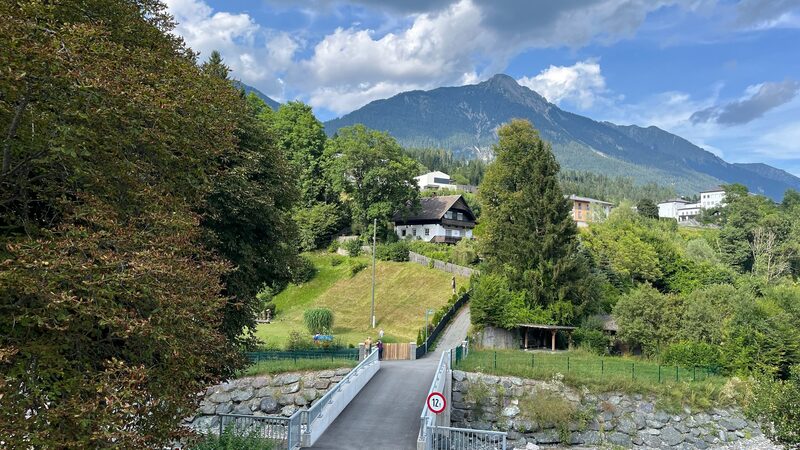 Heller Wohnbereich mit cremefarbenen Ledermöbeln, grünem Teppich und Blick in die offene Küche