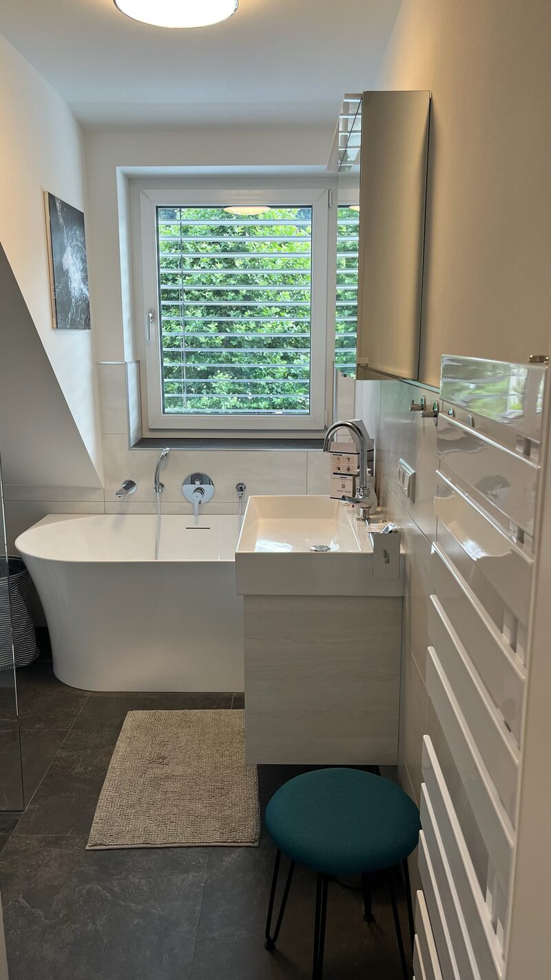 Moderner Essbereich mit vier dunkelgrauen Stühlen, Tisch in Marmoroptik und Blick ins Grüne