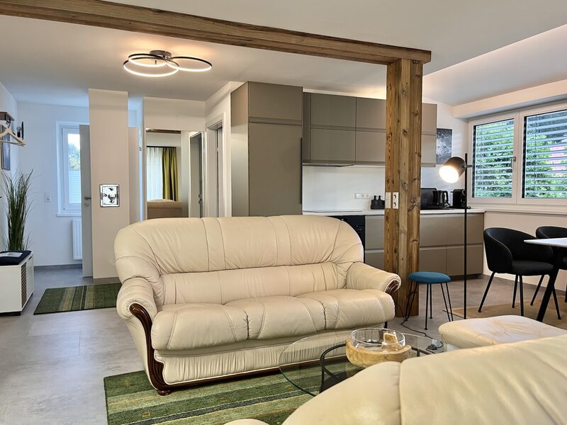 Wohnbereich mit cremefarbenem Sofa und Blick zur Küche