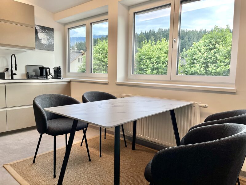 Essbereich mit Fensterfront und Ausblick auf grüne Bäume